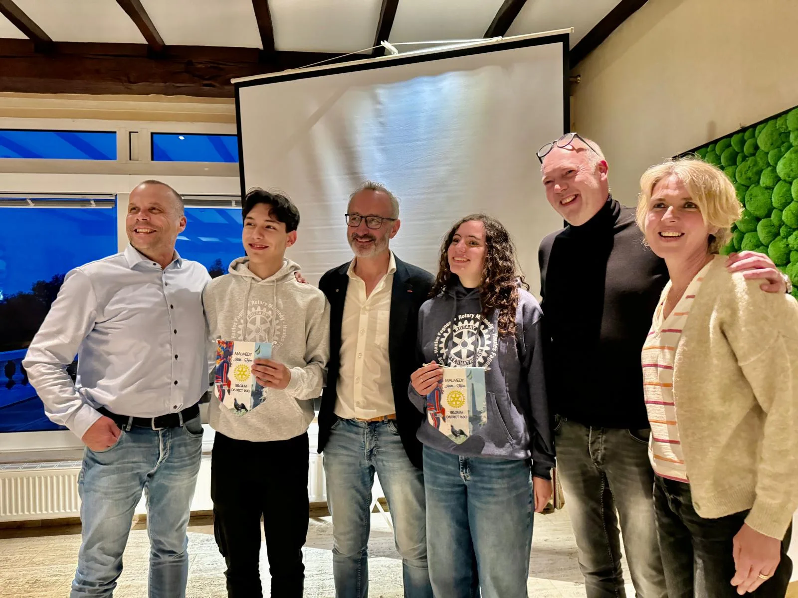Deux jeunes du programme d'échange, fanions du Rotary en main, entourés d'adultes
