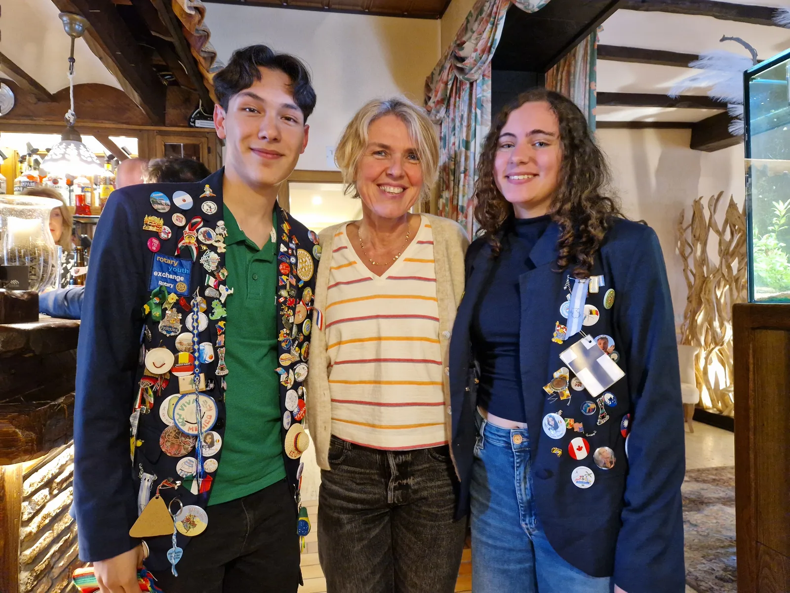 Deux jeunes en blazer bleu marine couvert de pin's du monde entier, aux côtés d'une adulte